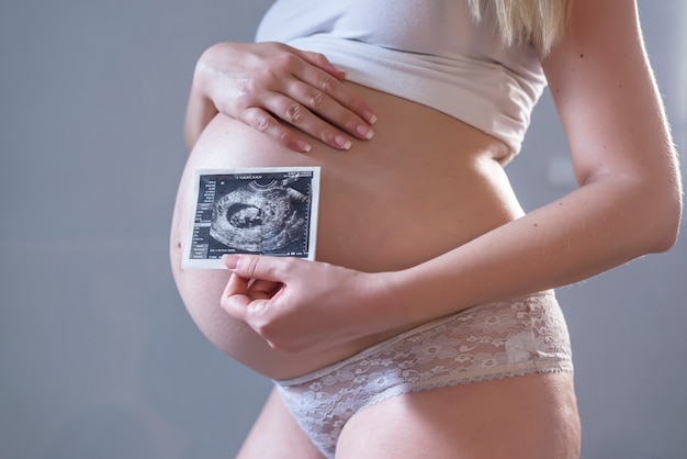 Mujer embarazada con foto de su futuro bebé