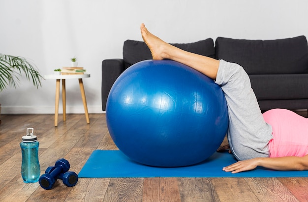 Mujer embarazada haciendo ejercicio en casa con pelota y pesas