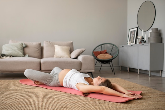 Mujer embarazada haciendo yoga en casa