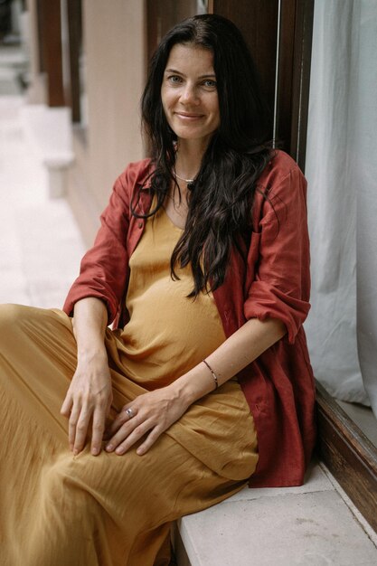 Mujer embarazada joven con cabello largo y oscuro en un lugar tropical