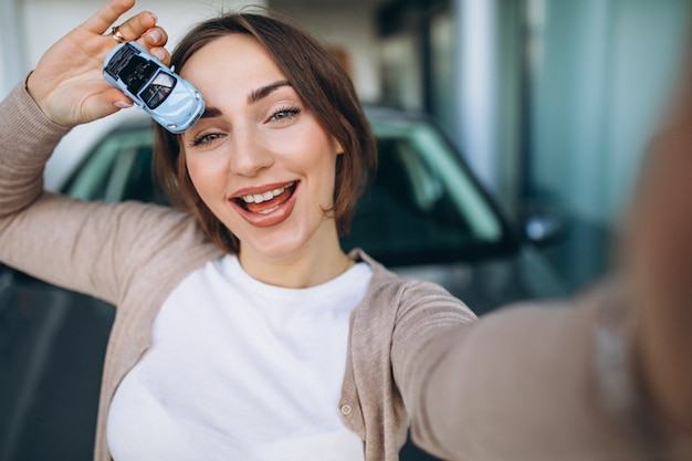 Mujer embarazada joven que elige un coche en una sala de exposición de automóviles