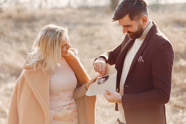 Mujer embarazada de pie en un parque con su esposo