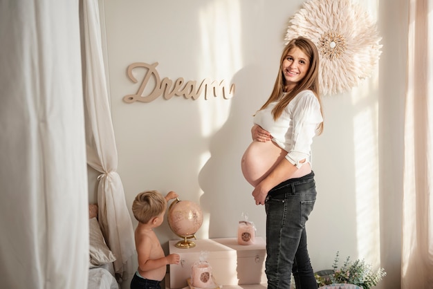 Mujer embarazada de pie con su hijo en una habitación interior