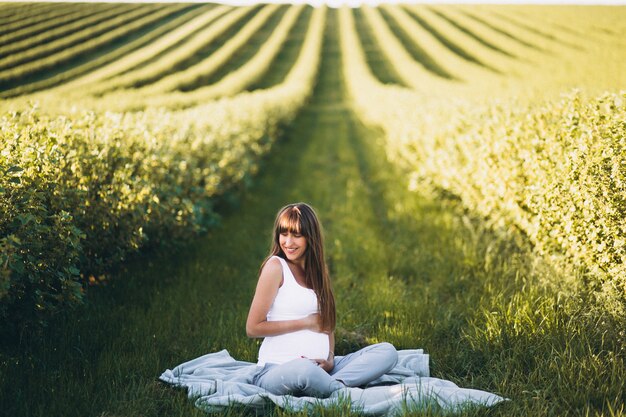 Mujer embarazada practicando yoga en el campo