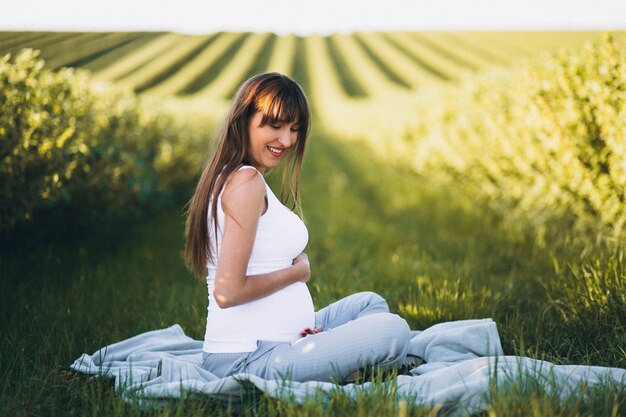 Mujer embarazada practicando yoga en el campo