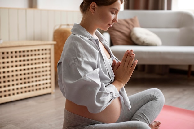 Mujer embarazada practicando yoga en casa
