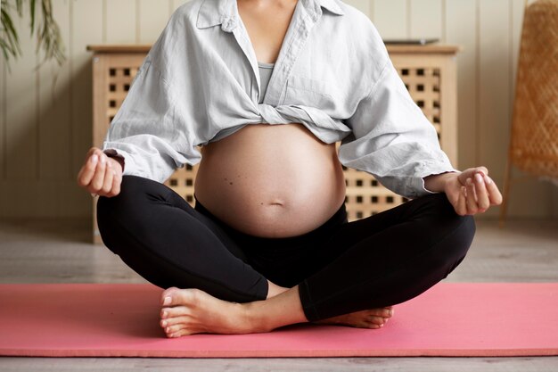 Mujer embarazada practicando yoga en casa