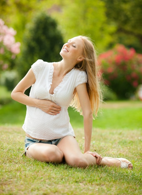 Mujer embarazada que se relaja en hierba