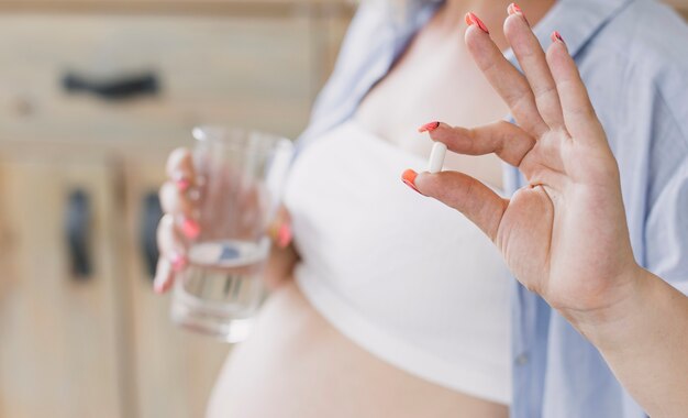 Mujer embarazada que sostiene una píldora