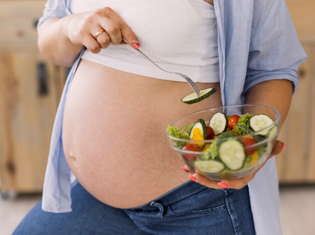 Mujer embarazada que sostiene un tazón de ensalada
