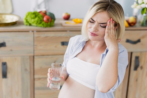 Mujer embarazada que tiene dolor de cabeza