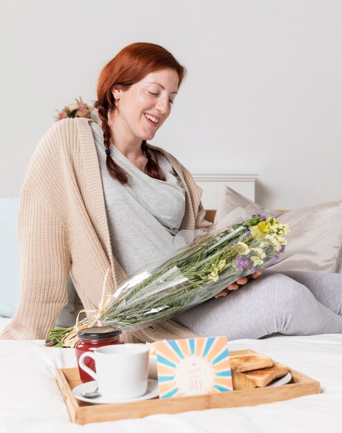 Mujer embarazada sonriente sorprendida en casa