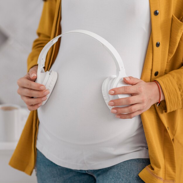 Foto gratuita mujer embarazada sosteniendo auriculares en su vientre