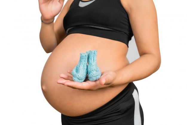 Mujer embarazada sosteniendo calcetines de bebé en el vientre