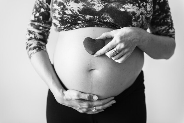 Mujer embarazada sosteniendo un corazón frente a su bebé topetón