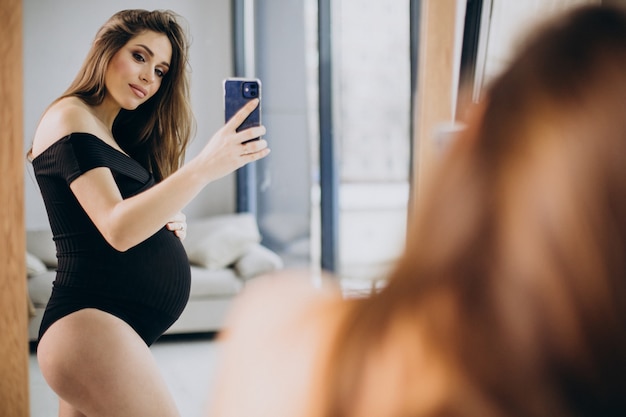 Mujer embarazada sosteniendo su vientre y mirando en el espejo