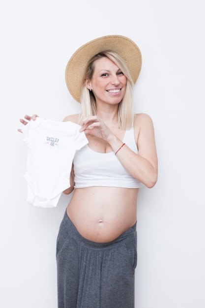 Mujer embarazada sujetando ropa de bebé