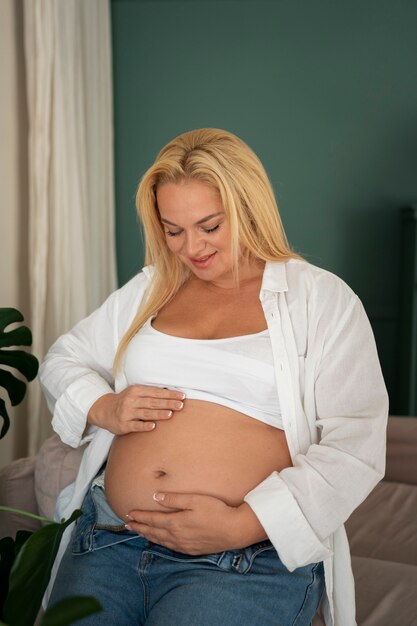 Mujer embarazada de tamaño mediano que pasa tiempo en el interior