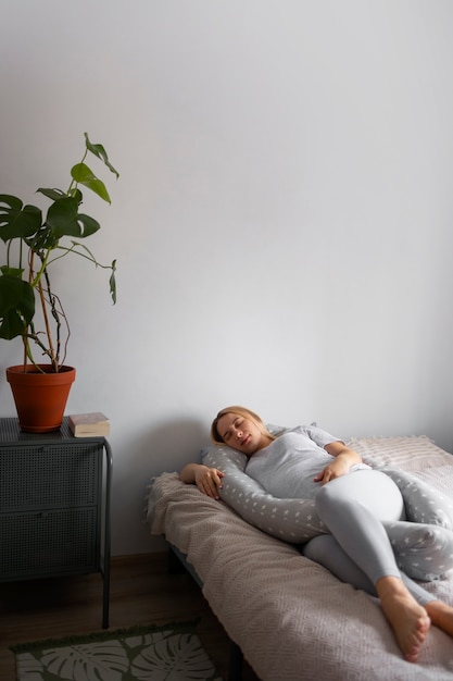 Mujer embarazada de tiro completo con almohada de lactancia