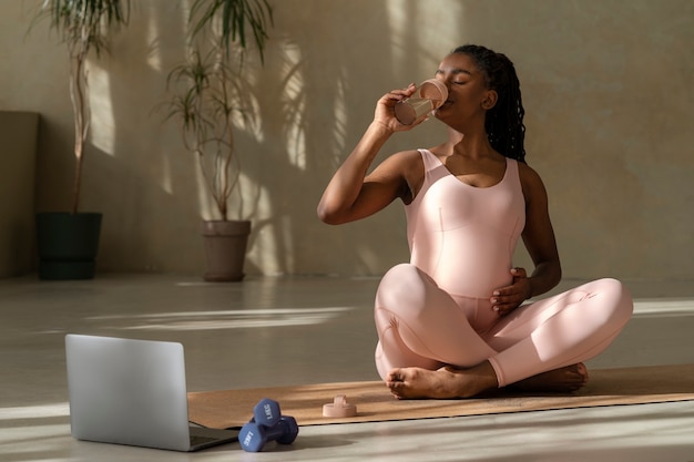 Foto gratuita mujer embarazada de tiro completo en estera de yoga