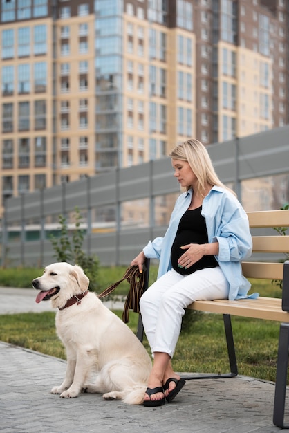 Mujer embarazada de tiro completo con lindo perro