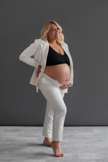 Mujer embarazada de tiro completo posando en el estudio