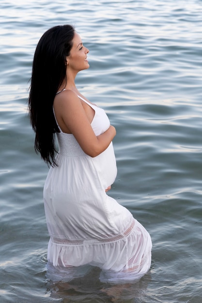 Foto gratuita mujer embarazada de tiro medio en la playa