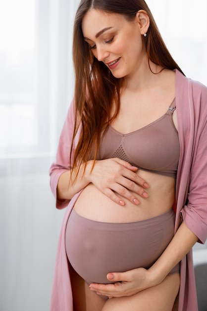 Foto gratuita mujer embarazada de tiro medio posando en casa