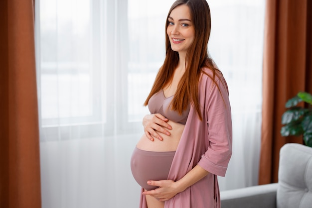 Foto gratuita mujer embarazada de tiro medio posando en casa