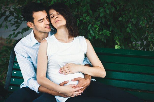 Mujer embarazada tocando las manos de su marido