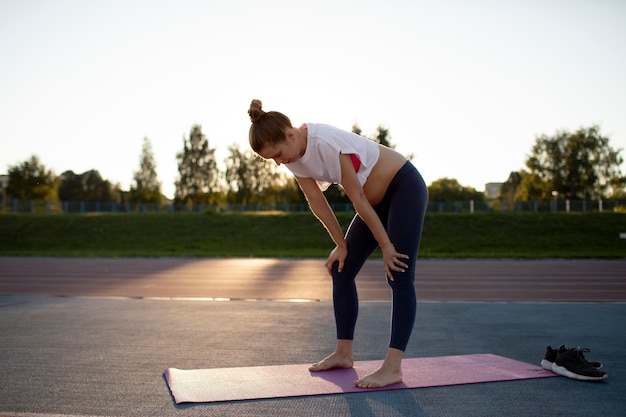 Foto gratuita mujer embarazada tomando un descanso del ejercicio al aire libre