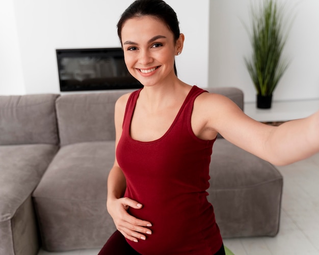 Foto gratuita mujer embarazada tomando un selfie mientras hace ejercicio