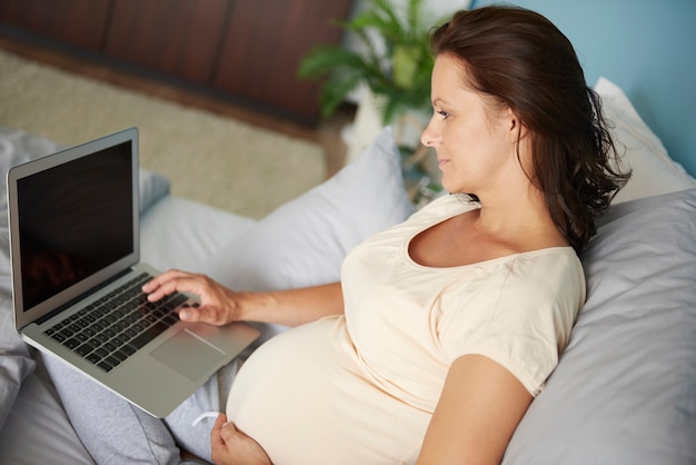 Mujer embarazada, usar la computadora portátil, en cama
