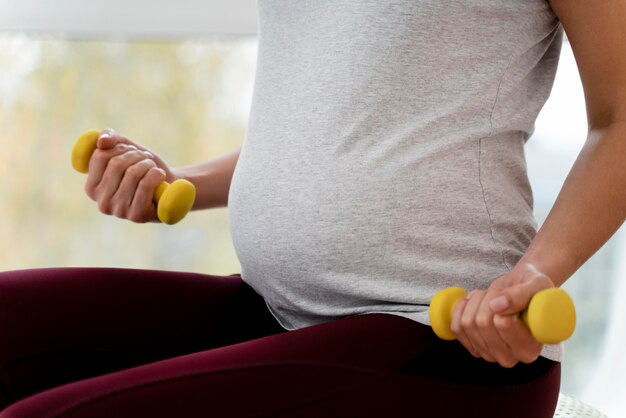 Mujer embarazada, utilizar, amarillo, pesas, primer plano