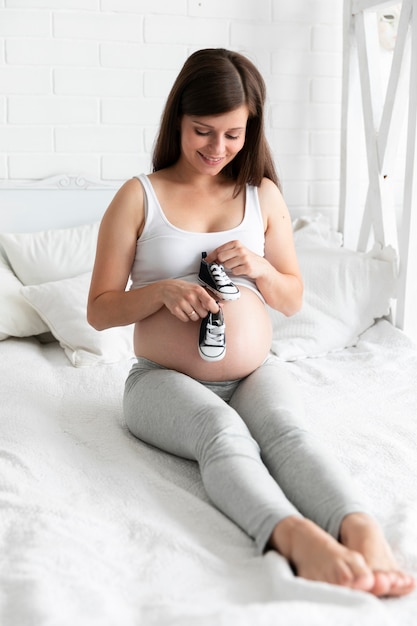 Foto gratuita mujer embarazada con zapatos pequeños para su bebé