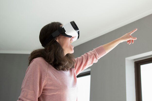 Mujer emocionada alegre en gafas de VR que señala a un lado