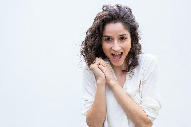 Mujer emocionada y alegre con las manos juntas jadeando