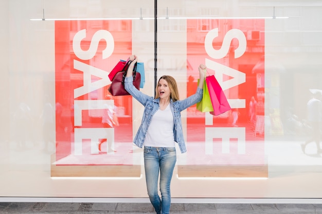 Foto gratuita mujer emocionada con coloridos bolsos de compras levantando sus brazos