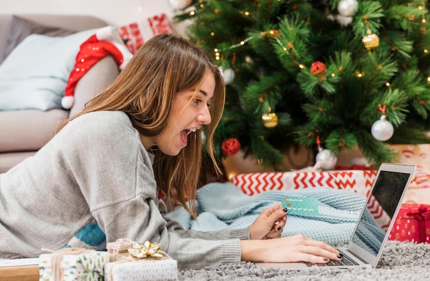 Mujer emocionada de compras en el árbol de navidad