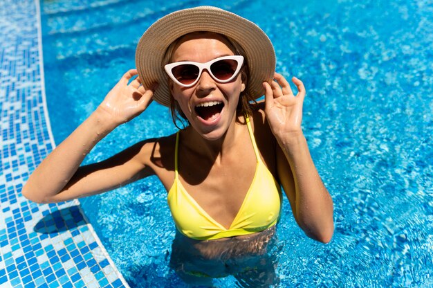 Mujer emocionada con gafas de sol en la piscina