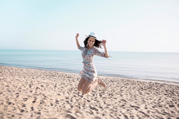 Foto gratuita mujer emocionada saltando en la playa