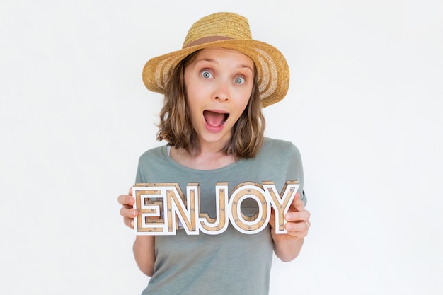 Mujer emocionada con sombrero con palabra de madera de disfrutar