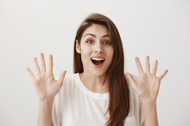 Mujer emocionada sorprendida mostrando las manos y sonriendo asombrado