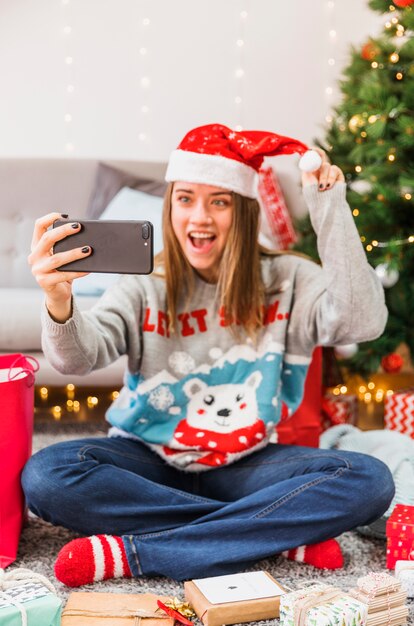 Mujer emocionada tomando selfie con gorro de navidad