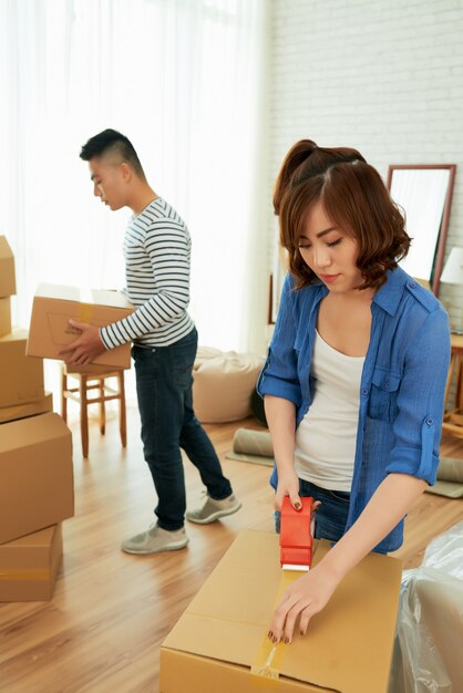 Mujer empacando cajas con su esposo llevando paquetes