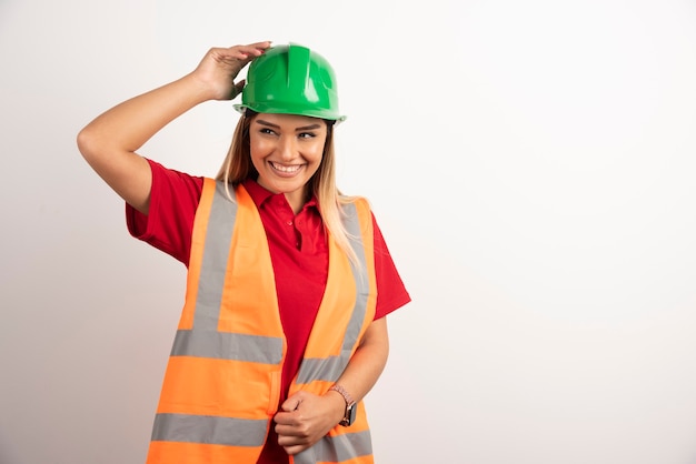 Mujer empleada en un chaleco y casco protector sobre fondo blanco.