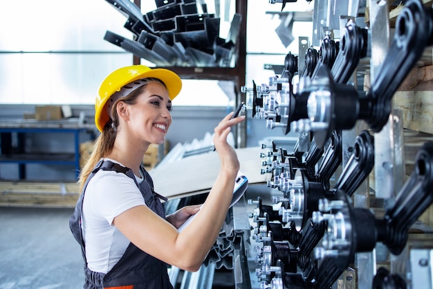 Mujer empleada industrial en uniforme de trabajo y casco de control de producción en la fábrica.
