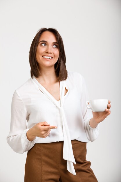 Mujer emprendedora, bebe café en el compañero de trabajo, sonríe