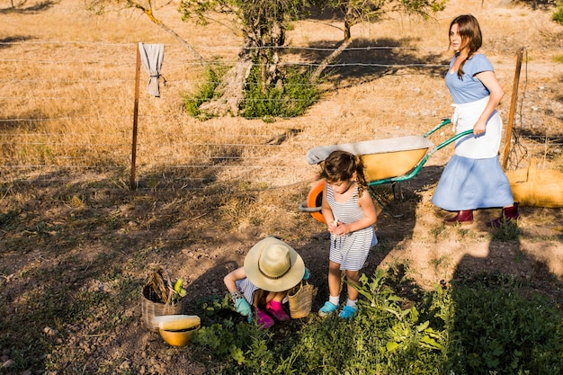 Mujer empujando la carretilla con su hija cosechando en el campo