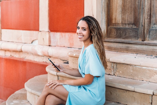 Foto gratuita mujer encantada navegando por el teléfono inteligente cerca de la baliza